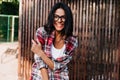 Cute lady with trendy hairstyle smiling on wooden background. Outdoor photo of ecstatic latin girl Royalty Free Stock Photo