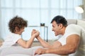 Game for boys. Cute latin boy and his father having fun together at home while armwrestling lying on the couch Royalty Free Stock Photo