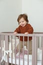 Cute laughing baby standing in round bed. Little girl learns to stand in her crib Royalty Free Stock Photo