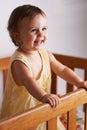 Cute, laughing and a child in a crib for playing, wake up or comfort in a bedroom. Happy, baby and a young kid in a Royalty Free Stock Photo