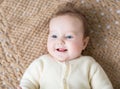 Cute laughing little baby on brown knitted blanket