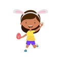 Cute laughing running girl with bunny ears holding egg in hand.