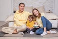 Cute laughing smiling parents with child son sitting by the bed and eating popcorn Royalty Free Stock Photo