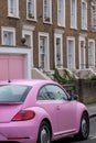 Cute pink Volkwagen Beetle retro style car, parked in front of a pink garage on a residential street in Notting Hill, London UK. Royalty Free Stock Photo