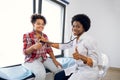 Cute likable mixed race teen girl and joyful African woman doctor, showing thumbs up during doctors checkup. Pediatrist Royalty Free Stock Photo