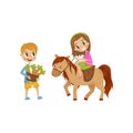 Cute litlle girl riding a horse, boy standing next to the horse with basket of carrots, equestrian sport concept cartoon Royalty Free Stock Photo