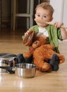 Cute littel boy sitting on the kitchen floor playing with pots