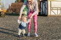 Cute little adorable blond toddler boy making first steps with mother support at city park at evening sunset time. Happy funny Royalty Free Stock Photo