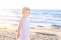 Cute little adorable toddler girl in white clothes walking on the beach on a warm sunny summer day. Holidays at sea. Family vacati Royalty Free Stock Photo