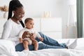 Cute little African American baby sitting on bed with mum Royalty Free Stock Photo