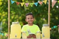 Cute little African-American boy with money at lemonade stand. Summer refreshing natural drink