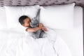 Cute little African-American boy with toy rabbit sleeping in bed, top view Royalty Free Stock Photo