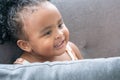 Cute little african girl with curly hair smiling. Portrait of happy female child sitting on sofa at home. Close-up face of 2 year Royalty Free Stock Photo