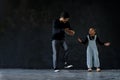 Cute little African kid boy and cool young Asian man teacher with tattoo are practice hip hop or freestyle dancing on cement floor Royalty Free Stock Photo