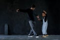 Cute little African kid boy and cool young Asian man teacher with tattoo are practice hip hop or freestyle dancing on cement floor Royalty Free Stock Photo