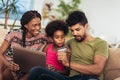 Cute little Afro-American girl and her beautiful young parents using laptop Royalty Free Stock Photo