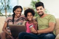 Cute little Afro-American girl and her beautiful young parents using laptop Royalty Free Stock Photo