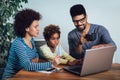 Little Afro-American girl and her beautiful young parents using a laptop and doing shopping online Royalty Free Stock Photo