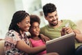Cute little Afro-American girl and her beautiful young parents using laptop Royalty Free Stock Photo