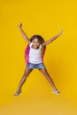 Cute little afro girl jumping over yellow studio background Royalty Free Stock Photo