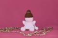 Cute little angel crocheted, handmade art. Amigurumi one white angel without face wears brown hat, sits on pink Royalty Free Stock Photo