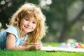 Cute little artist boy. Child boy draws in park laying in grass having fun on nature background. Royalty Free Stock Photo