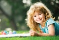 Cute little artist boy. Child boy draws in park laying in grass having fun on nature background. Royalty Free Stock Photo