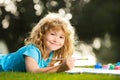 Cute little artist boy. Kid draws in park laying in grass having fun on nature background. Kids creative education Royalty Free Stock Photo