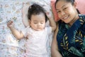 Cute little Asian baby girl sleeping on bed beside mother, mother smile and looking at camera Royalty Free Stock Photo