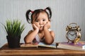 Cute little asian baby toddler making boring face while reading books with alarm clock