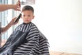 Cute little Asian boy child getting a haircut at the hairdresser`s barber shop, Kid cut with hairdresser`s machine