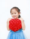 Cute little Asian child girl holding red heart pillow on white background. Happy valentines day Royalty Free Stock Photo