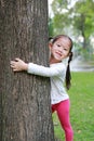 Cute little Asian child girl hugging a big tree in the garden Royalty Free Stock Photo