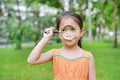 Cute little Asian child girl looking through magnifiying glass on at grass outdoors Royalty Free Stock Photo
