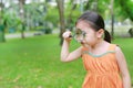 Cute little Asian child girl looking through magnifiying glass on at grass outdoors Royalty Free Stock Photo