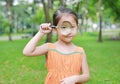 Cute little Asian child girl looking through magnifiying glass on at grass outdoors Royalty Free Stock Photo