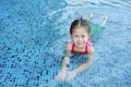 Cute little Asian child girl in a mermaid suit has fun sitting poolside