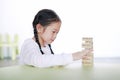 Cute little Asian child girl playing wood blocks tower game for Brain and Physical development skill in a classroom. Focus at Royalty Free Stock Photo