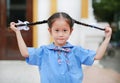 Cute little Asian child girl in school uniform holding her two tied ponytails hairs Royalty Free Stock Photo