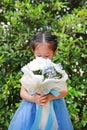 Cute little Asian child girl smelling Bouquet of flowers in the garden Royalty Free Stock Photo