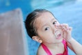 Cute little Asian child girl with snot runny nose while swimming at pool on cold weather day