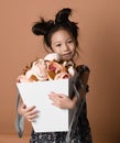 Cute little asian girl in beautiful spring dress hugs a big basket of big white flowers pion that she just got Royalty Free Stock Photo