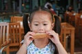 Cute little asian girl bite bread sheet. Asian girl having breakfast Royalty Free Stock Photo