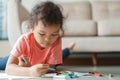 Cute little asian girl drawing homework and writing with color Wax crayons on paper at home Royalty Free Stock Photo