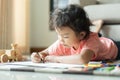 Cute little asian girl drawing homework and writing with color Wax crayons on paper in her home Royalty Free Stock Photo