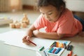 Cute little asian girl drawing homework and writing with color Wax crayons on paper in her home Royalty Free Stock Photo