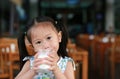 Cute Little asian girl drinking glass of fresh milk in coffee shop Royalty Free Stock Photo