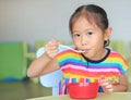 Cute little Asian girl eating cereal with cornflakes and milk on the table. Children having breakfast at morning Royalty Free Stock Photo