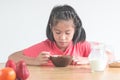 Cute little Asian girl eating cereal with the milk in the kitche Royalty Free Stock Photo