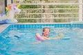 Cute little Asian girl having fun playing with inflatable swim ring in outdoor swimming pool on hot summer day Royalty Free Stock Photo